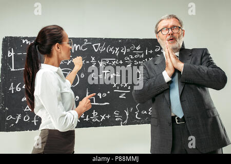 Male professor and young woman against chalkboard in classroom Stock Photo