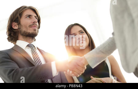 Businesspeople  shaking hands against room with large window loo Stock Photo