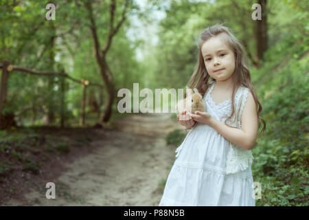 Little girl in the fairy forest. She is holding a small rabbit in her hands. Stock Photo