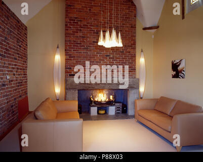 Leather sofas in modern country living room with fireplace in brick wall Stock Photo