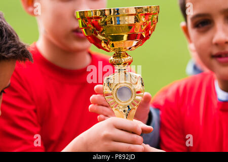 Kids soccer football - young children players celebrating with a trophy after match on soccer field Stock Photo