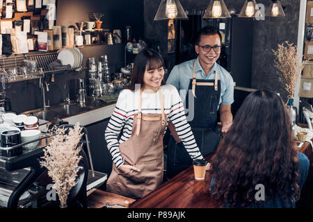 Asia barista waiter and waitress take order from customer in coffee shop,Two cafe owner writing drink order at counter bar,Food and drink business con Stock Photo