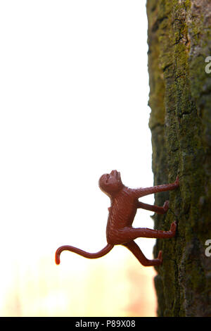 Vertical closeup shot of a red toy monkey on a green surface Stock Photo