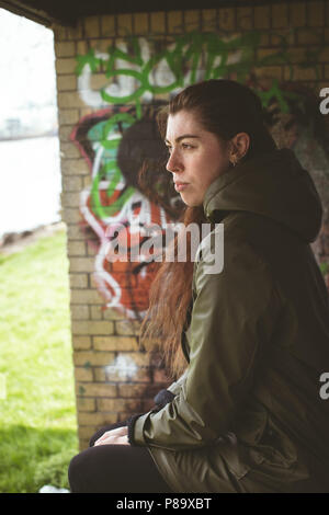 Woman relaxing against graffiti wall Stock Photo