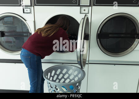 Woman doing laundry in laundromat Stock Photo