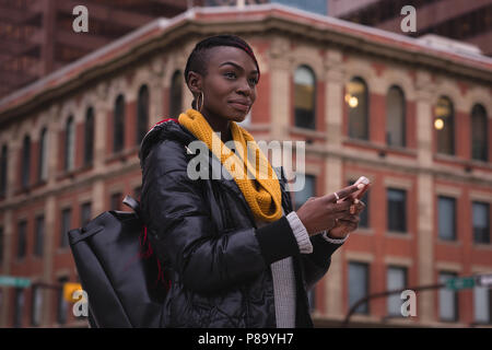 Woman using mobile phone in city street Stock Photo