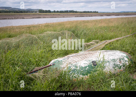 View across the River Nith at Glencaple, Scotland.  Small upturned boat with Haaf net in the foreground, an example of traditional fishing methods. Stock Photo