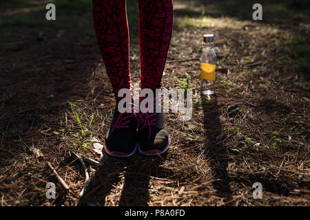 Female athlete wearing sneakers standing next to water bottle Stock Photo