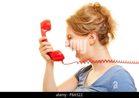 Young angry woman loudly roars in a red telephone receiver Stock Photo