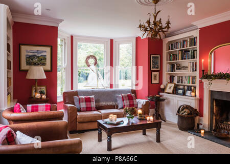 Brown leather three-piece suite and bookcase in Regency home Stock Photo