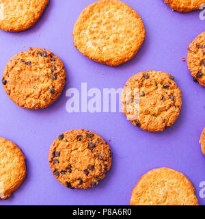 Assorted American traditional old fashioned cookies. Oatmeal and chocolate chips cookies on a purple background. Top view and square image. Stock Photo