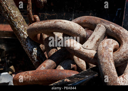 Close-up of a huge, heavy, rusted chain lying in a sunlit pile, emphasizing its size and heft, 2018. Stock Photo