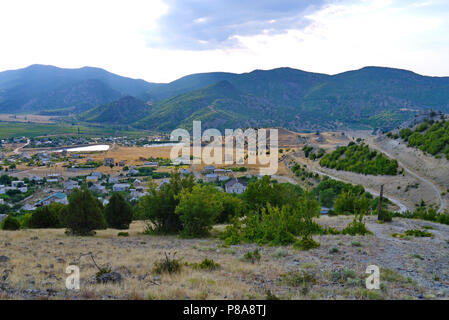 A neat village lying in a picturesque valley with rare trees growing on the slopes and cobwebs of dirt roads around. . For your design Stock Photo