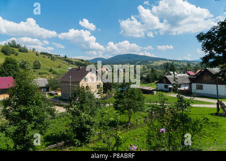 modern and old private residential houses with garden plots and fruit tree gardens in a village on a mountain valley under a blue cloudy sky. place of