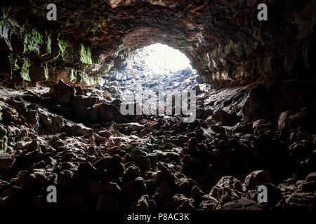 Exit from the cave. Underground trail through lava tube. Stock Photo