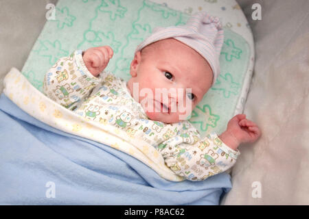 A new born wakes from  a nap in his crib at home. Stock Photo