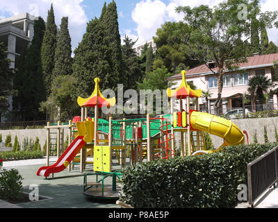 playground with slides painted in bright colors with beautiful greenery of flowerbeds growing near . For your design Stock Photo