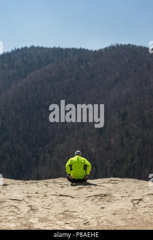 Man sitting on the ledge of a cliff, Tomasovsky vyhlad, Slovak paradise, Slovakia. Stock Photo