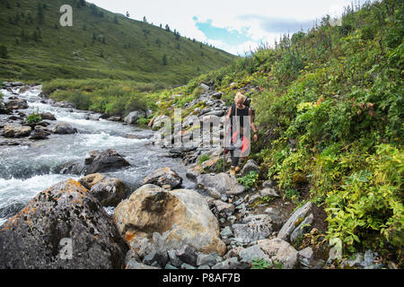 young backpacker walking near river in Altai, Russia Stock Photo