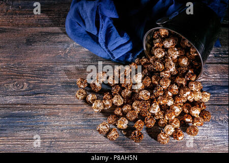 Caramel popcorn on a wooden background. Low key lighting. Selective focus. Close-up. Top view Stock Photo