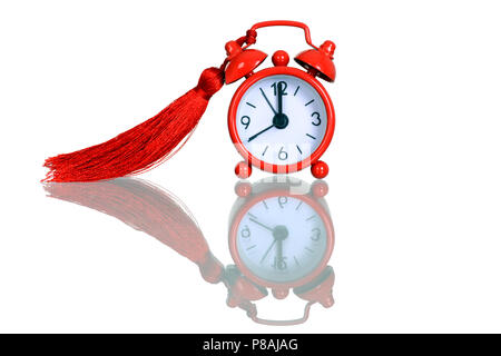 Old red alarm clock with tassel, Red round alarm clock shows 5 minutes to midnight Stock Photo