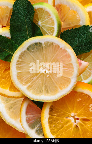 Citrus background. Many slices of lemon, orange, lime and mint leaves lie together. A lot of fruits. Vitamins and a healthy snack. Stock Photo