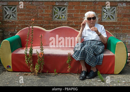Elderly English lady on a garden sofa during the long hot summer of 2018 Stock Photo