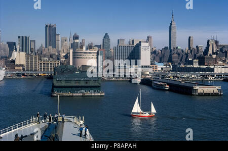 The skyline of New York City in New York, USA, as seen in 1971 looking from the Hudson River past ship piers and the elevated West Side Highway (12th Avenue) to buildings in Midtown Manhattan, including the towering Empire State Building to the right. This waterfront area has changed greatly in appearance with the 21st-Century establishment of the Hudson River Park that features pedestrian and bicycle paths connecting recreational facilities for many leisure and sports activities. Historical photograph. Copyrighted by Michele & Tom Grimm. Stock Photo