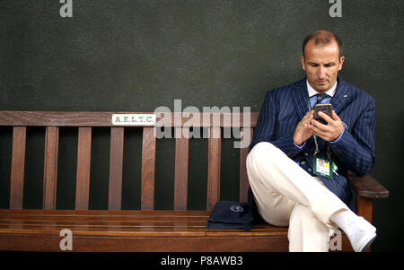 A lines judge sits on a bench in the grounds on day eight of the Wimbledon Championships at the All England Lawn Tennis and Croquet Club, Wimbledon. Stock Photo