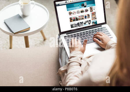 cropped shot of woman at home sitting on couch and using laptop with amazon website on screen Stock Photo