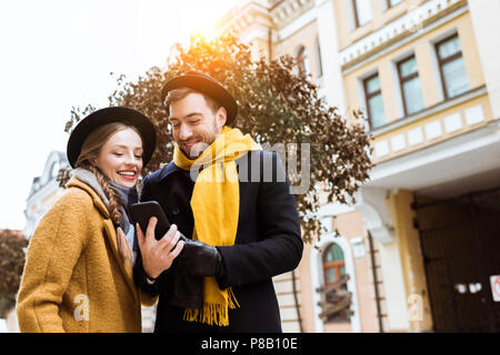 beautiful young couple in autumn outfit looking at smartphone Stock Photo
