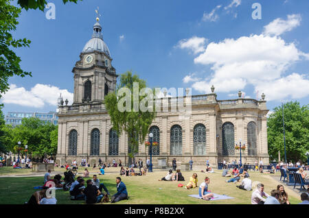 Office workers sit outside at lunchtime in the warm summer sunshine in the grounds surrounding St Philip's Cathedral in Birmingham Stock Photo