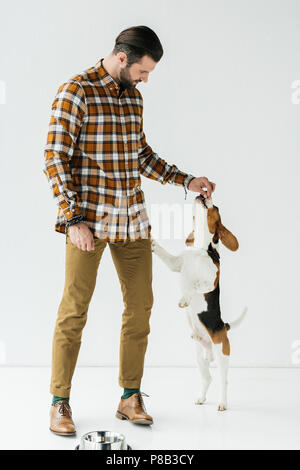 handsome man feeding dog on white Stock Photo