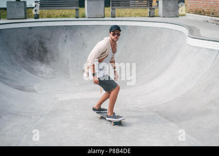 handsome skater skating in middle of pool at skatepark Stock Photo