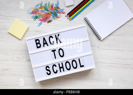 Education concept. 'Back to school' word on lightbox, accessories for study over white wooden background, top view. Flat lay, overhead. Stock Photo