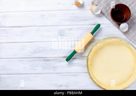 raw base of dough for baking in a baking dish and ingredients for greek pie with cheese and tomatoes, copy space, top view Stock Photo