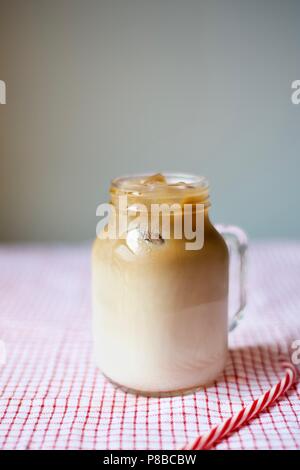 iced coffee in a mason jar mug with a straw on table cloth on gray background, summer drink, beverage concept Stock Photo