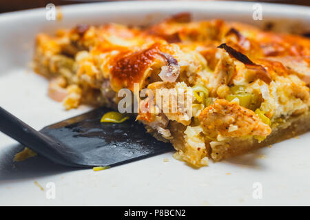 Slice of tart with meat, mushrooms, and cheese on white plate Stock Photo