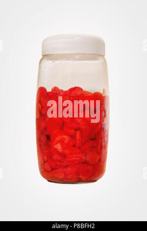 Conserved ginger on the vinegar. Red shoga gari into slices on a transparent jar with no brand, isolated on white. Stock Photo