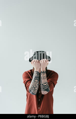 tattooed man covering face with hands isolated on white Stock Photo