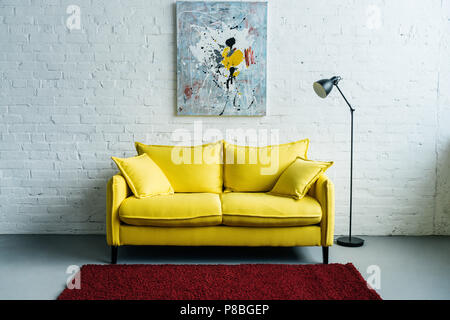 Interior of cozy living room with painting on wall, sofa and floor lamp beside Stock Photo