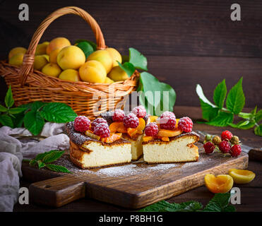 curd pie with raspberries and apricots on a brown wooden board, close up Stock Photo