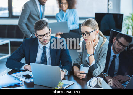 multicultural businesspeople looking at laptops in workspace Stock Photo