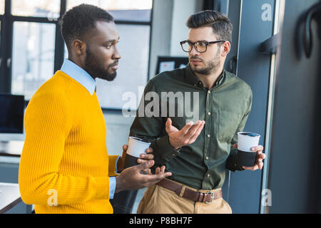 multicultural businessmen talking during coffee break in office Stock Photo