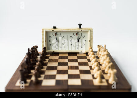 Chess board with figures set for new game and chess clock isolated on white Stock Photo