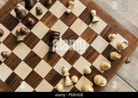 Chess board with scattered chess figures on wooden surface Stock Photo