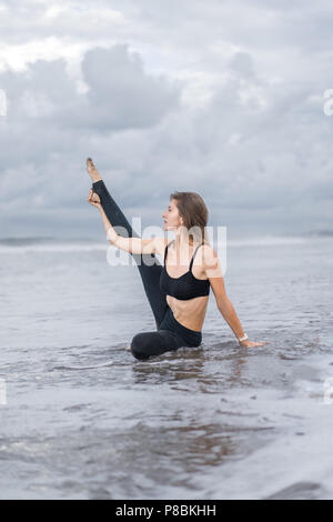 sporty young woman practicing yoga in ocean Stock Photo