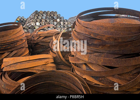 Pile of rusty metal hoops in front of stacks of discarded whisky casks / barrels, Speyside Cooperage, Craigellachie, Aberlour, Grampian, Scotland, UK Stock Photo