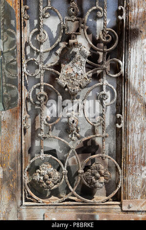 Ornate cast iron door decoration, peeling paint, surface rust Stock Photo