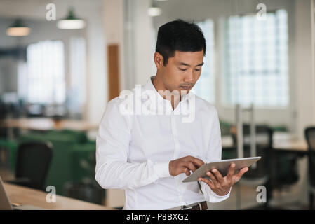 Focused Asian businessman using a tablet in an office Stock Photo